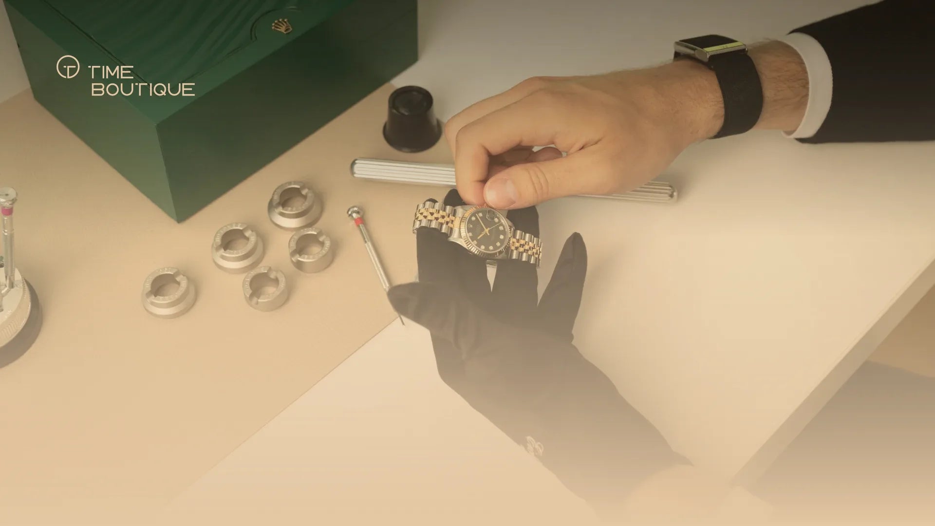 Ladies' Rolex in steel and gold being inspected with a glove, next to the green Rolex box